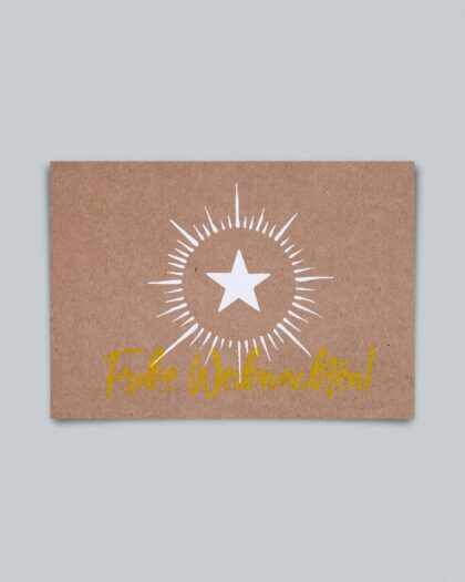Eine Weihnachtsgrußkarte im Querformat auf braunem Kraftpapier. In der Mitte ist eine stilisierte weiße Sternenexplosion abgebildet, bestehend aus einem zentralen weißen fünfzackigen Stern, um den herum ein Kranz aus kurzen, radialen Strichen strahlt. Darunter steht in goldener, geschwungener Handschrift der Gruß "Frohe Weihnachten!".